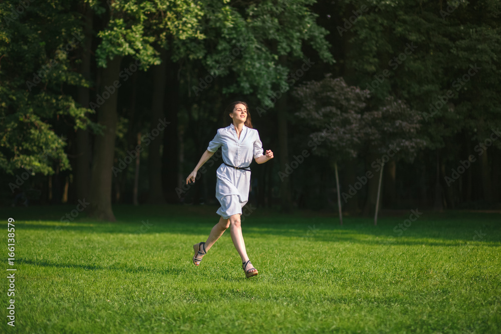 happy brunette woman run in forest green lawn at sunny day happy brunette woman run in forest green lawn at sunny day