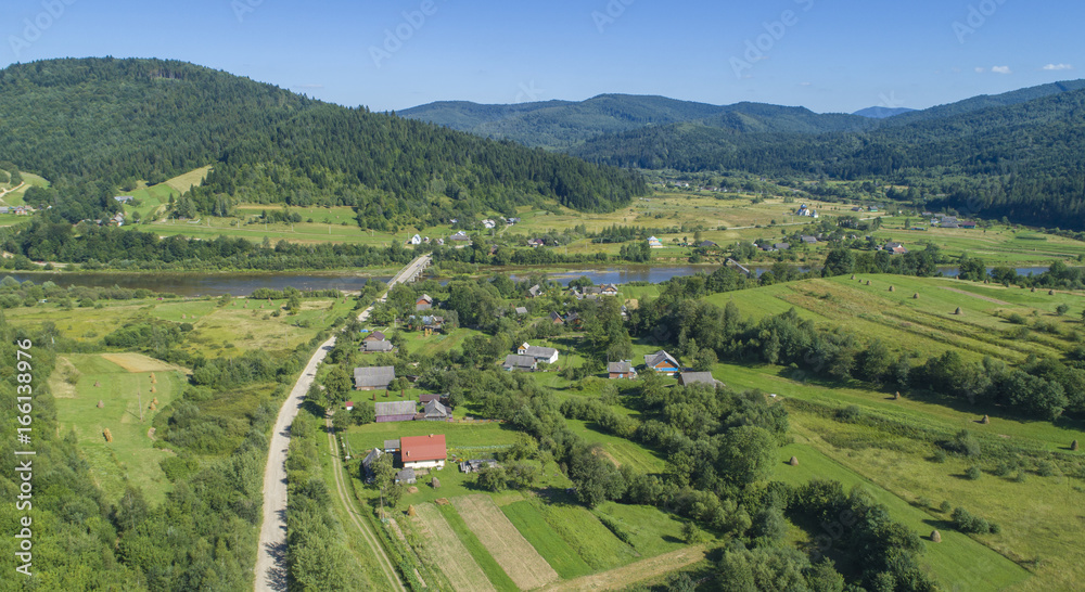  a beautiful summer landscape shot from a bird's eye view. mountains, river, green fields and villages.