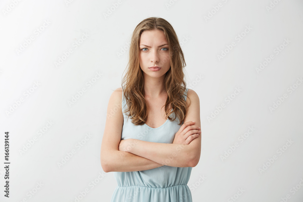 Offended displeased young girl frowning looking at camera with crossed arms over white background. Offended displeased young girl frowning looking at camera with crossed arms over white background.