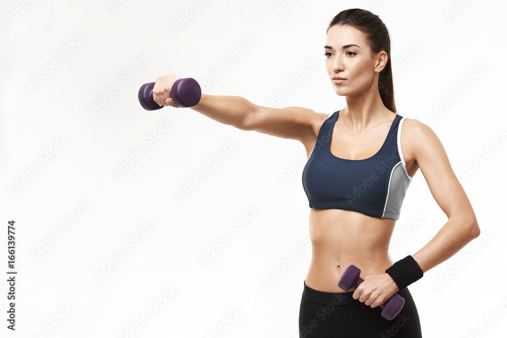 Sportive beautiful girl in sportswear training arms with dumbbells over white background. Sportive beautiful girl in sportswear training arms with dumbbells over white background.