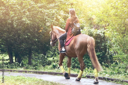 Girl riding a horse in a park toning