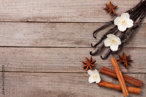 Vanilla sticks with cinnamon and flower on a old wooden background with copy space for your text. Top view