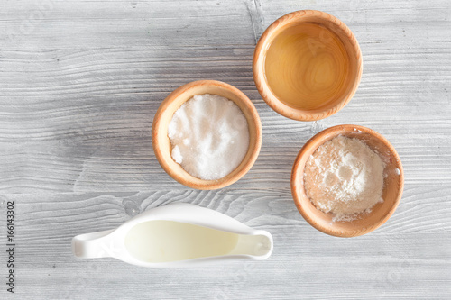 Put the dough. Flour, salt, mik, oil, rolling pin on light wooden table background top view copyspace