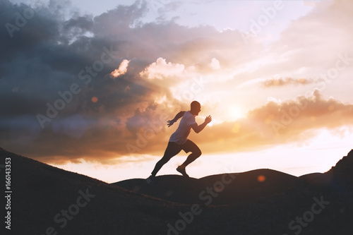 Canvas Print Athlete runs quickly through the hills outdoors at sunset