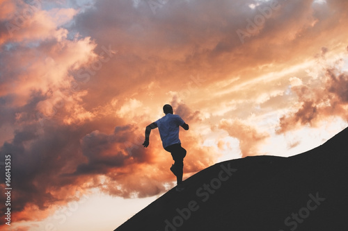 Male sportsman running around the hills at sunset. Athlete trains in nature