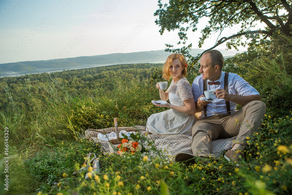 Attractive Couple Enjoying Romantic Sunset Picnic in the Countryside Attractive Couple Enjoying Romantic Sunset Picnic in the Countryside