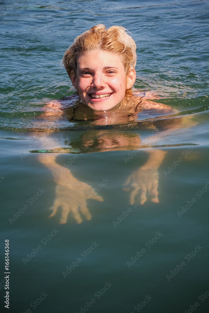 Cute lovely woman swimming in the water on a summer day