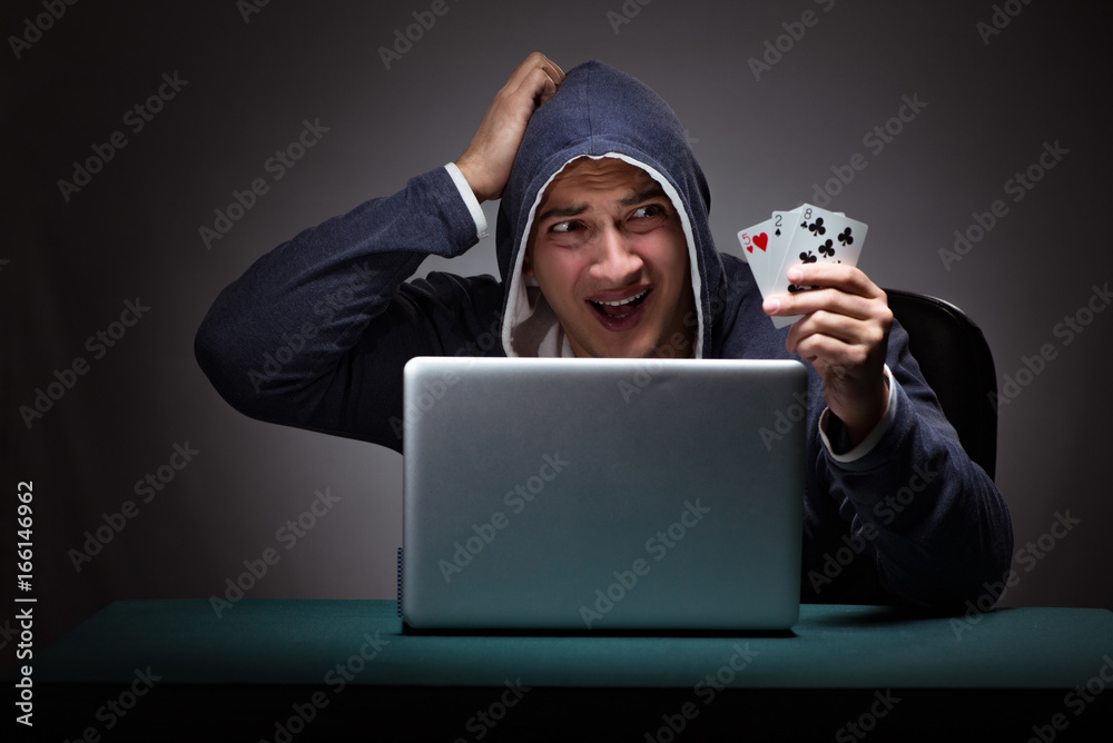Young man wearing a hoodie sitting in front of a laptop computer Young man wearing a hoodie sitting in front of a laptop computer