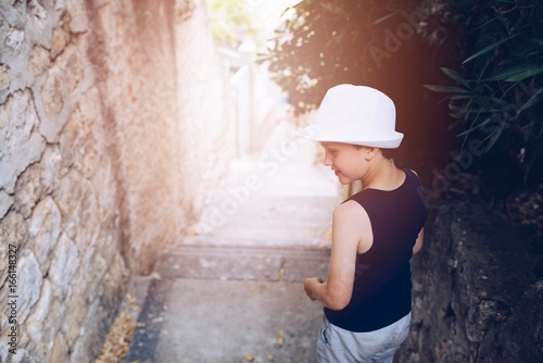 Child in white hat walking on narrow street of old town