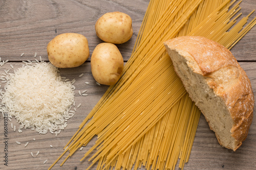 Spaghetti, rice, potatoes, and bread, on a wooden table