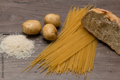 Spaghetti, rice, potatoes, and bread, on a wooden table