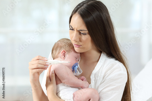 Mother checking thermometer with an ill baby photo