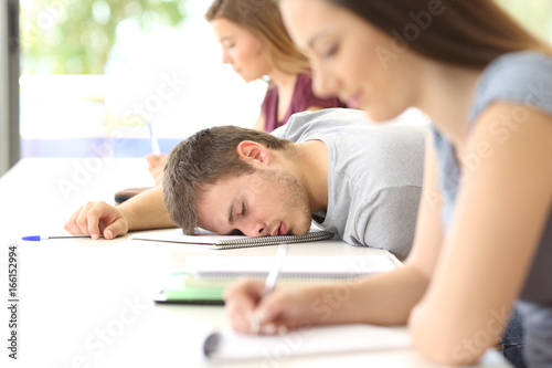 Tired student sleeping in a class at classroom