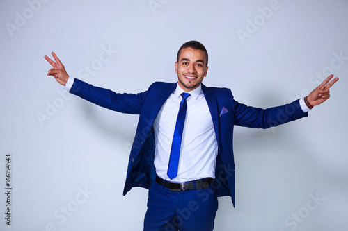 Young successful businessman with raised arms standing on white background. Business, people and office concept