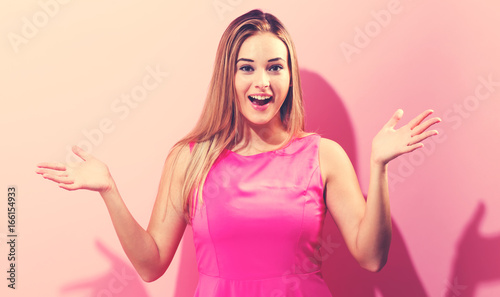 Surprised young woman posing on a pink background