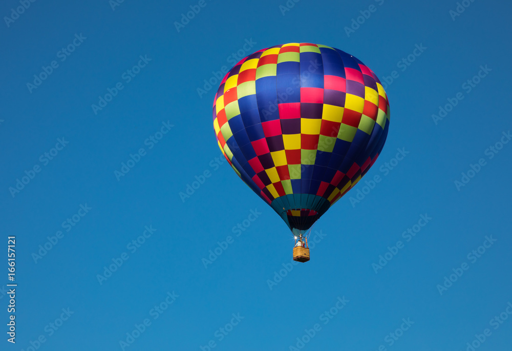 Teardrop shaped hot air balloon in rainbow colors in air with blue sky background Teardrop shaped hot air balloon in rainbow colors in air with blue sky background