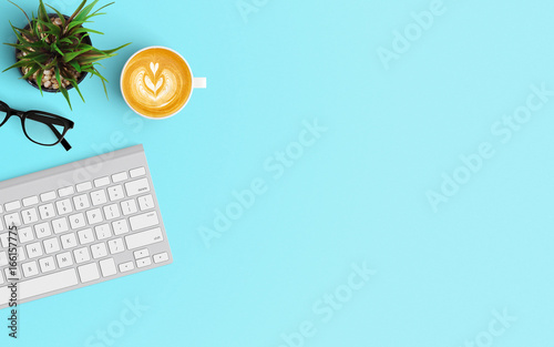 Modern workspace with keyboard and coffee cup copy space on color background. Top view. Flat lay style.