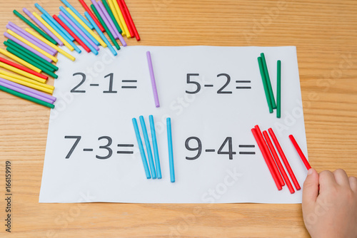 kid learning simple subtraction by counting numbers of sticks