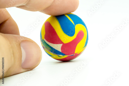 Index or pointing finger touching colorful rubber marble ball isolated on white photo