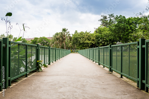 Concrete bicycle bridge with green fence in park © smilepoker
