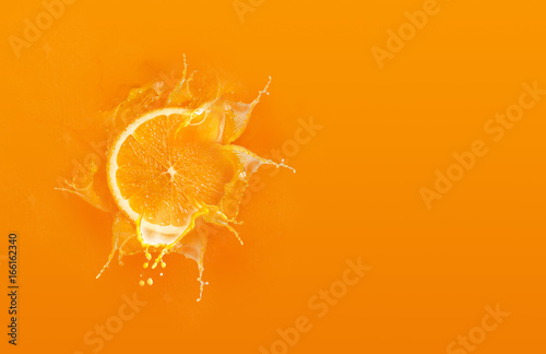 Canvastavla Slide cut piece of orange drop on orange background with orange juice splash wat