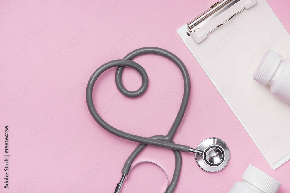 The stethoscope with heart shape with pill bottles on pink background.