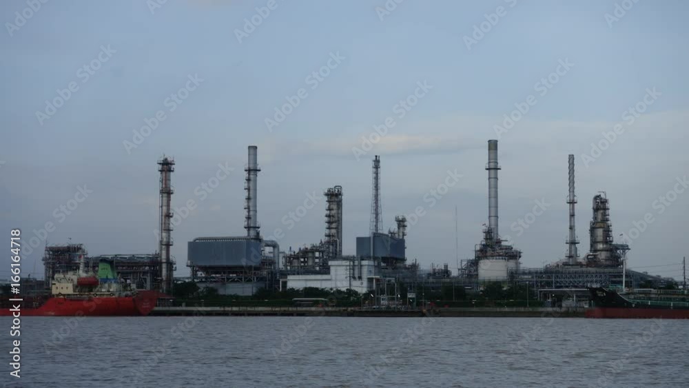 Time lapse, Oil refinery plant and ship, river at twilight Time lapse, Oil refinery plant and ship, river at twilight
