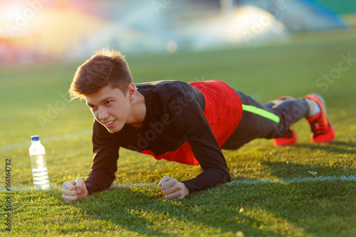Young athlete doing an exercise in training on a green football field