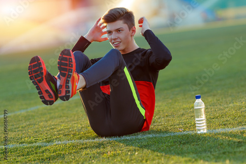 Young athlete doing an exercise in training on a green football field