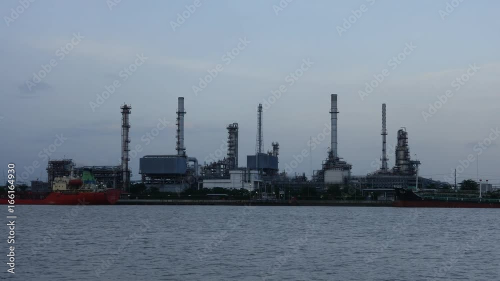 Time lapse, Oil refinery plant and ship, river at twilight Time lapse, Oil refinery plant and ship, river at twilight