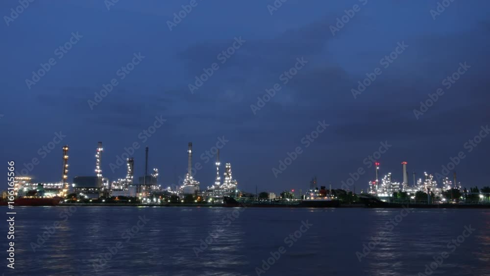 Time lapse, Oil refinery plant and ship, river at twilight Time lapse, Oil refinery plant and ship, river at twilight