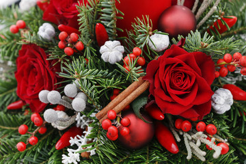 Christmas decoration with candle, red roses, fir, brunia and cinnamon sticks.