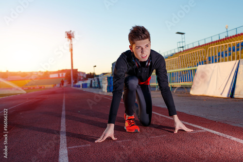 Young athlete runner in a position of readiness to start running in a sports stadium