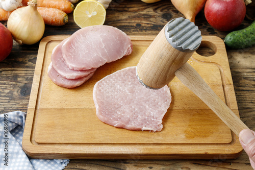 Meat mallet and beaten piece of veal on cutting board photo