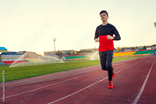 young man is training at a sports stadium in sports uniform at sunset