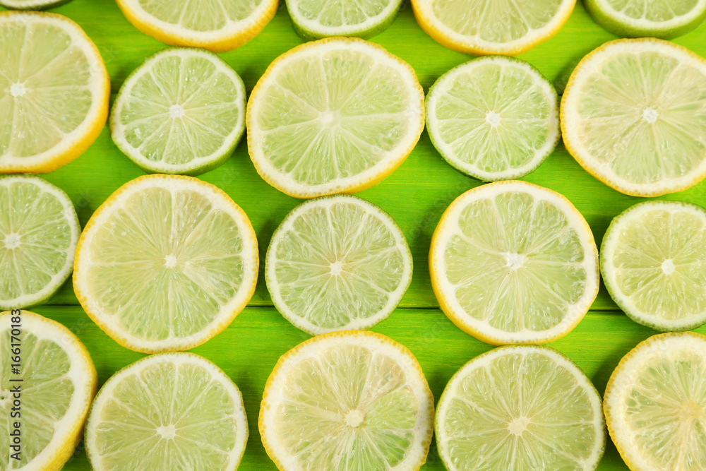 Slices of limes and lemons on green wooden table