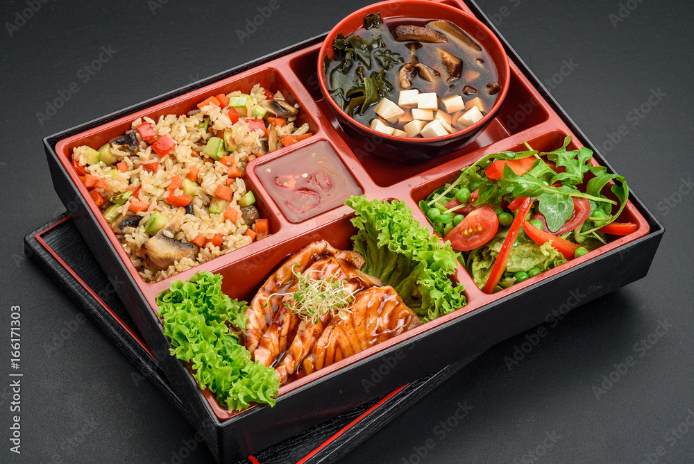 Japanese cuisine. Bento. Miso soup , rice salmon fillet and salad. Concrete background.
