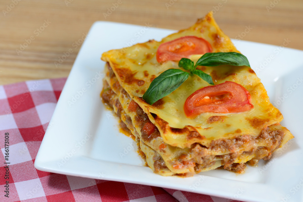Tasty lasagne served on a wooden table. Italian food background. Close-up. Tasty lasagne served on a wooden table. Italian food background. Close-up.