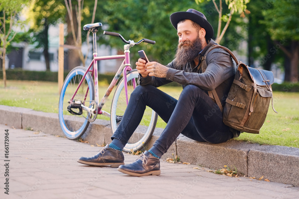 Obraz premium A man sits on a step and using a smartphone.