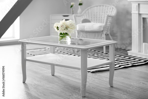 Interior of light room with beautiful peonies in vase on table