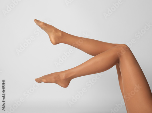 Legs of beautiful young woman in tights on light background
