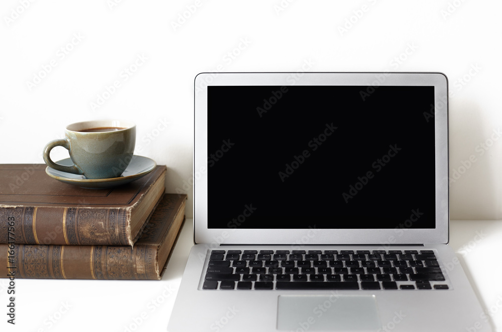 Cropped shot of open laptop computer, two books and mug of coffee or tea resting on white desk. Technology, communication, job, occupation and leisure concept. Freelancer's workplace. Mock up Cropped shot of open laptop computer, two books and mug of coffee or tea resting on white desk. Technology, communication, job, occupation and leisure concept. Freelancer's workplace. Mock up