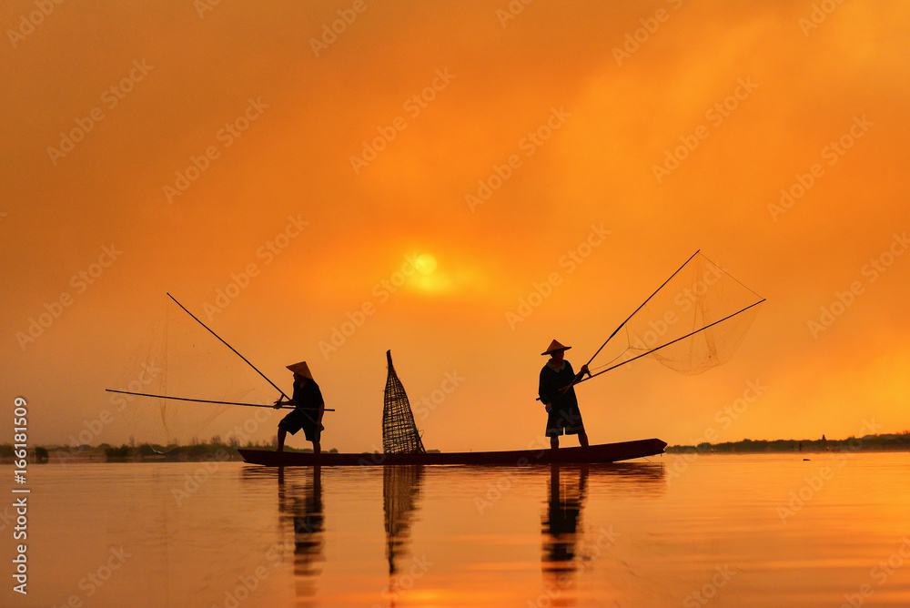 Silhouette fisherman trowing the nets on during sunrise,Thailand