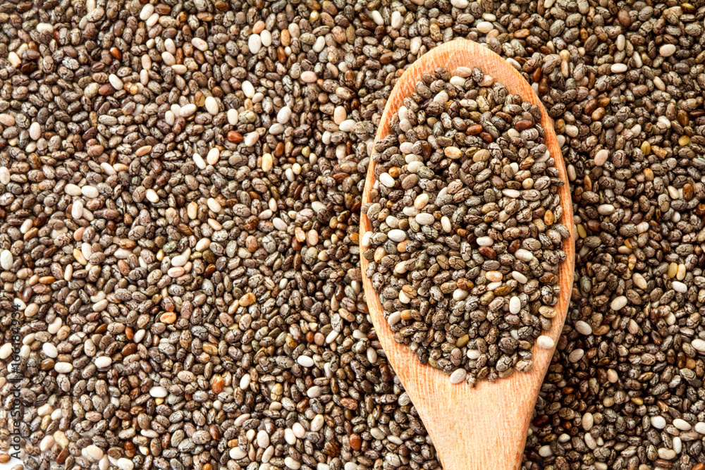 Close up chia seeds in wooden spoon on chia seeds background Close up chia seeds in wooden spoon on chia seeds background