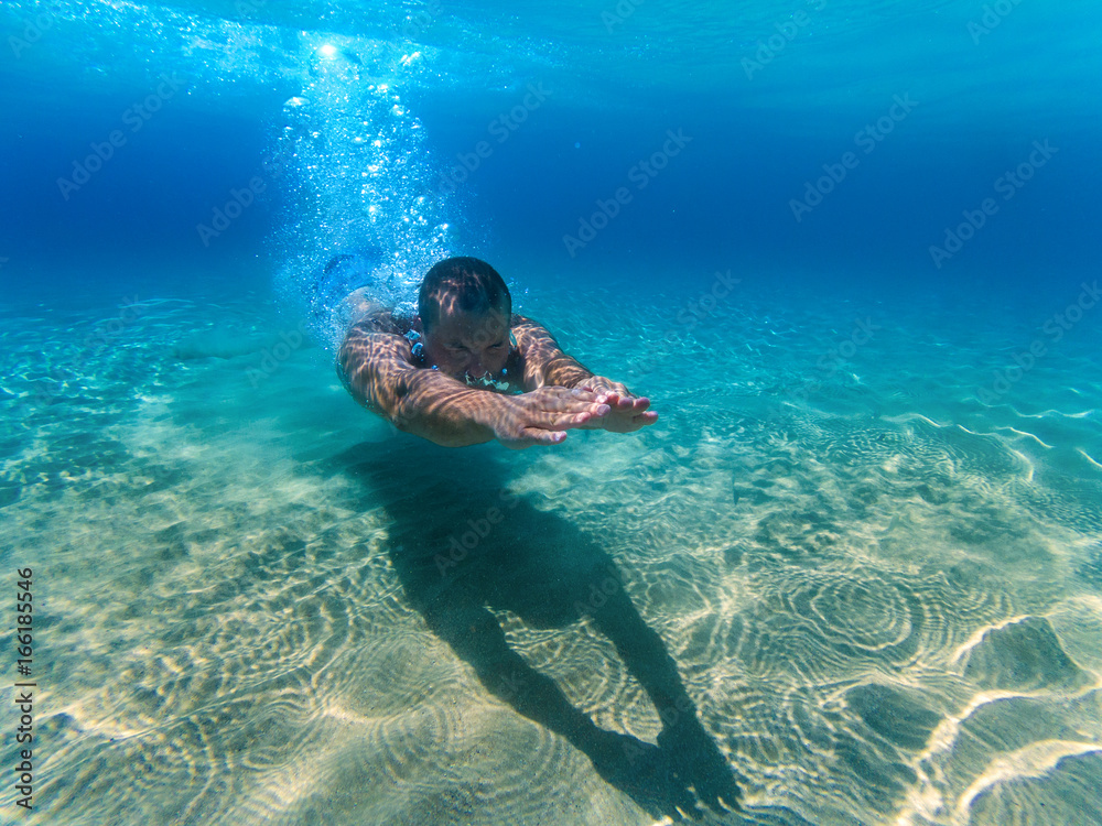 Man swimming underwater in the sea.