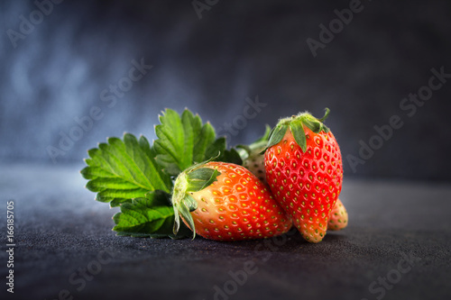 Fototapeta Naklejka Na Ścianę i Meble -  Close up Red Strawberries and leaf with black stone background