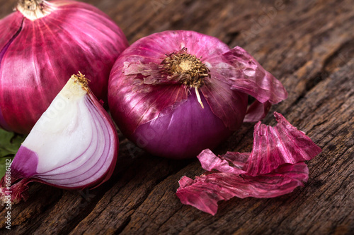 Close up of the  sliced red onion and whole bulb onion on a wooden background