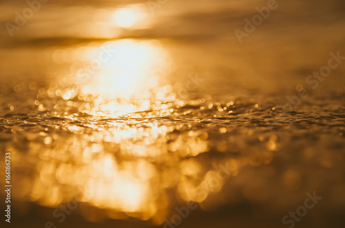 Blur tropical sunset beach with bokeh sun light wave abstract background.