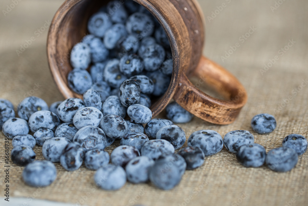 Blueberries sprinkled from rustic cup Blueberries sprinkled from rustic cup
