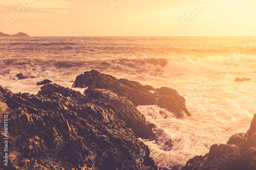 Wave splash on rock in sunset beach background. Copy space of outdoor summer vacation and business travel adventure concept.